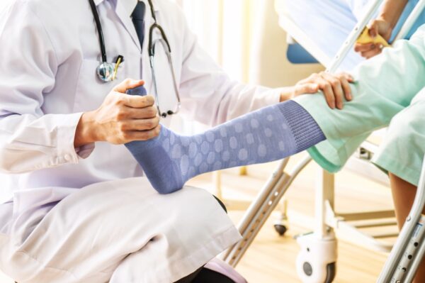 Doctor and patient - Doctor examining of the leg from the knee and ankle and training broken leg patient in hospital - physical therapy concept
